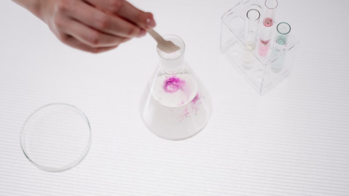 Close-up of a hand conducting a chemical experiment with flasks and test tubes.